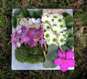 Composition fleurs piquées dans la mousse dans un plateau métallique