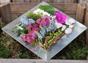 Composition fleurs piquées dans la mousse dans un plateau métallique