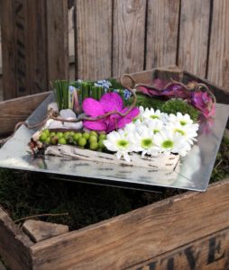 Composition fleurs piquées dans la mousse dans un plateau métallique