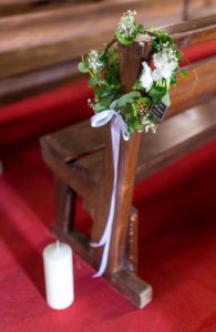 Petite couronne végétative poiur décoration de banc d'église avec gypsophile et fleurs blanche. Bougie au pied du banc.