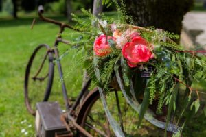 Composition de pivoine corail de rose pastel et de graminées dans une corbeille en osier sur un vieux vélo