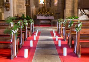 Décoration des bancs d'église avec couronne végétative verte et blanche plus bougie