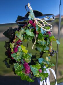 Décoration de poignée de voiture de mariée avec couronne de lierre de baie noires et d'amarante. Lien en lin et ruban blanc