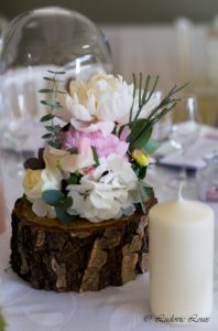 Décoration de table fleurie composée de pivoines blanches et roses sur des rondins
