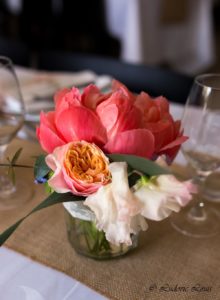 Petit centre de table constituée de pivoine corail de rose pastel et de pois de senteur dans un bocal en verre