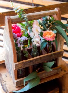 Décoration floral d'un ancien casier à bouteille en bois avec de l'eucaliptus des rose saumon et des pivoine corail