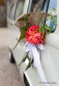 Décoration de poignée d'une voiture de mariée avec pivoine corail et graminée et ruban blanc